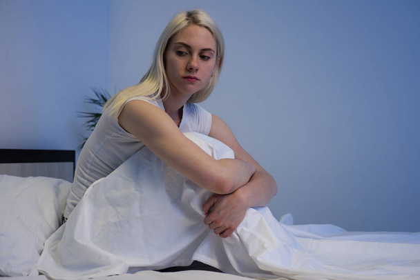 Mujer deprimida triste sentada en su cama tarde en la noche, ella es pluma
 - Foto, Imagen