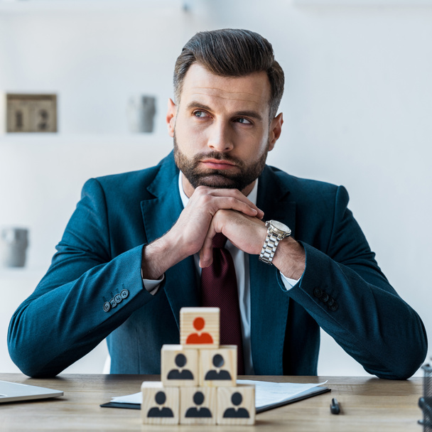 selective focus of pensive and bearded man with clenched hands near wooden cubes  - Photo, Image