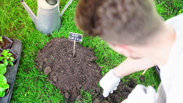 częściowy widok ogrodnika za pomocą łopaty podczas pracy w ogrodzie na trawie - Materiał filmowy, wideo