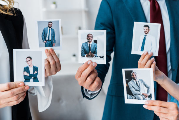 cropped view of recruiters touching photos while standing in office  - Photo, Image