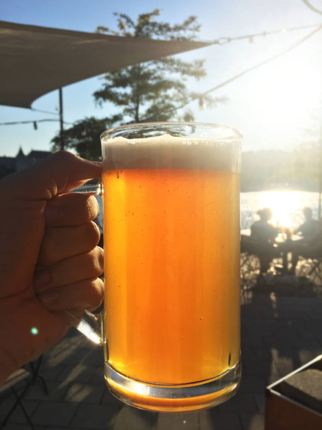ήλιος φωτίζει το ποτήρι της μπύρας στο χέρι - Φωτογραφία, εικόνα