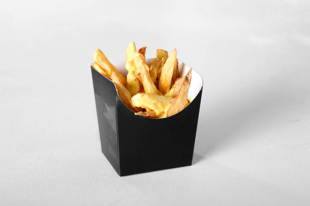 close up view of french fries in paper container on grey background - Zdjęcie, obraz