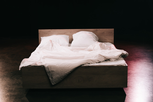 oreillers doux sur des draps blancs propres dans la chambre à coucher sur noir
  - Photo, image