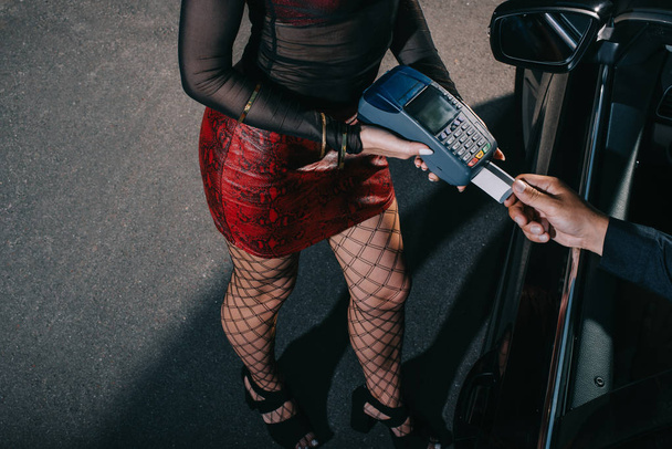 Overhead-Ansicht des Kunden mit Kreditkarte bezahlen, während Prostituierte mit Kreditkartenlesegerät  - Foto, Bild