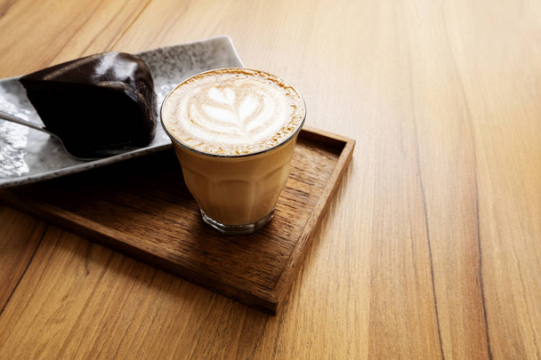 Hot Latte, Latte Art patroon, mooi met taarten op een houten tafel - Foto, afbeelding