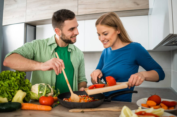 Jeune couple prépare le repas dans leur cuisine
.  - Photo, image