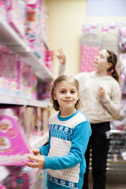 Дівчина-підліток вибирає подарунок молодшій дівчині в магазині
. - Фото, зображення