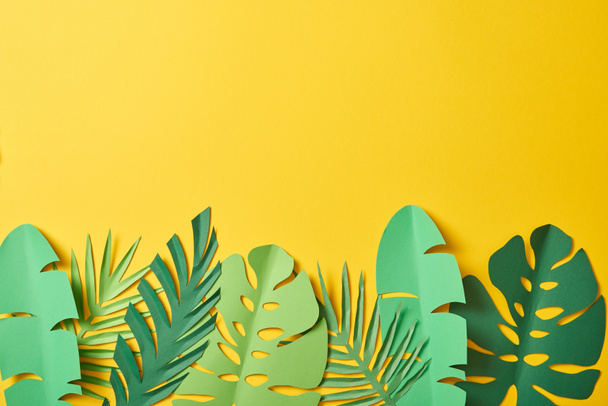 top view of paper cut green palm leaves on yellow background with copy space - Fotografie, Obrázek
