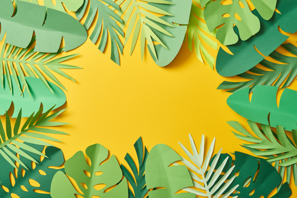 top view of paper cut green palm leaves on yellow background with copy space - Photo, image