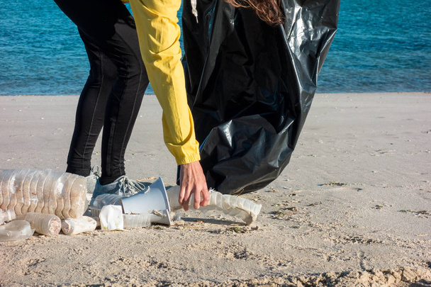 Donna che raccoglie spazzatura e plastica che pulisce la spiaggia con un sacco della spazzatura. Attivista volontario per l'ambiente contro il cambiamento climatico e l'inquinamento degli oceani
. - Foto, immagini