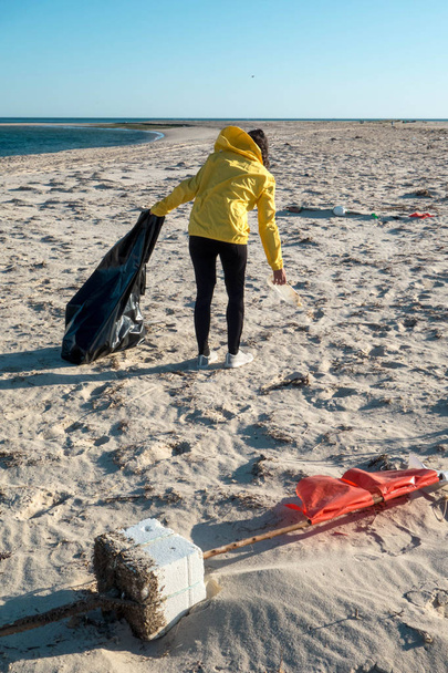 Femme ramassant des ordures et des plastiques nettoyant la plage avec un sac poubelle. Militant bénévole pour l'environnement contre le changement climatique et la pollution des océans
. - Photo, image
