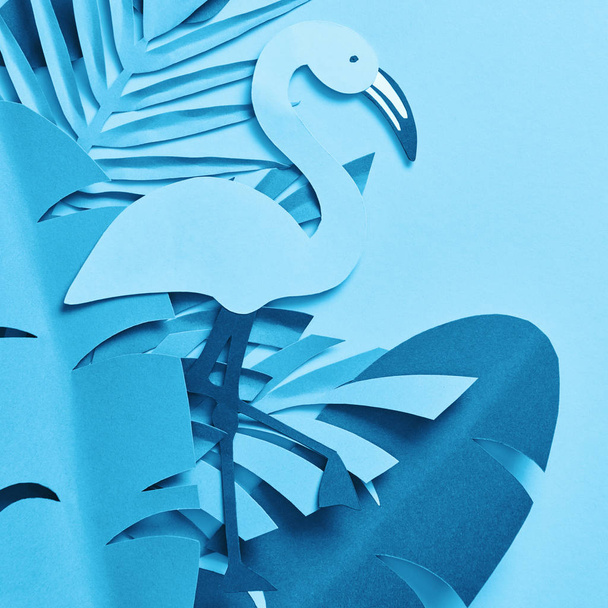 Draufsicht auf blaues Papier geschnittene Palmblätter und Flamingo auf blauem Hintergrund - Foto, Bild