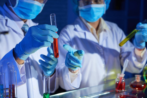 Vědci pracující v laboratorních a diskutování zkumavek s barevnou tekutinami - Fotografie, Obrázek