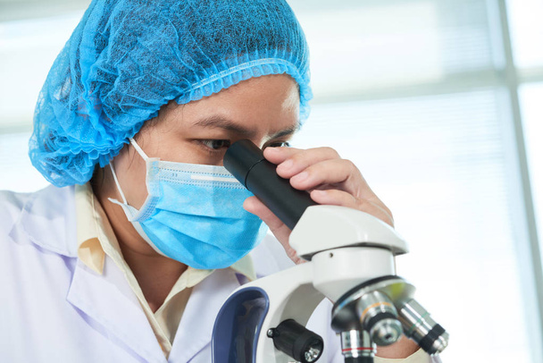 Βιετναμέζικες γυναίκες βιολόγοι που αναζητούν κάποια ουσία μέσω του μικροσκόπιο - Φωτογραφία, εικόνα