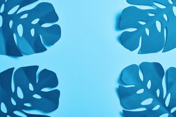 vista superior de hojas de palma cortadas en papel minimalista azul sobre fondo azul con espacio para copiar
 - Foto, Imagen