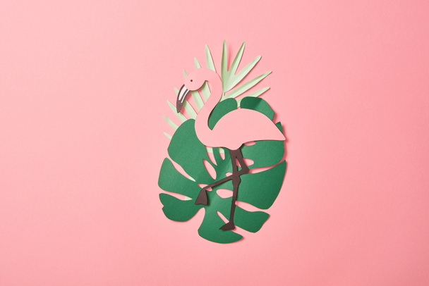 top view of paper cut flamingos on green palm leaves on pink background - Foto, imagen
