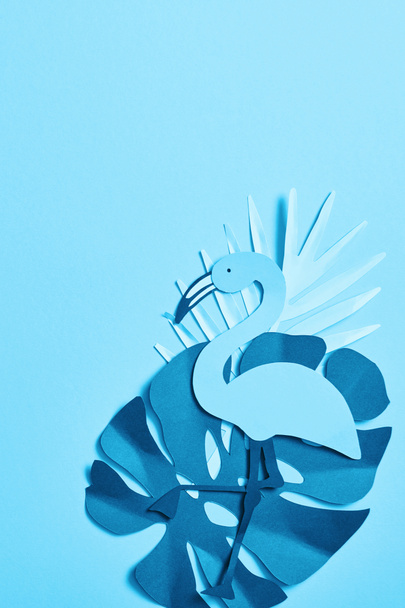 Top uitzicht van blauwe minimalistische papier gesneden Palm bladeren en Flamingo op blauwe achtergrond met Kopieer ruimte - Foto, afbeelding