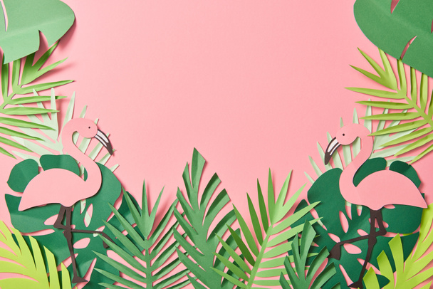 top view of paper cut flamingos on green palm leaves on pink background with copy space - Photo, Image