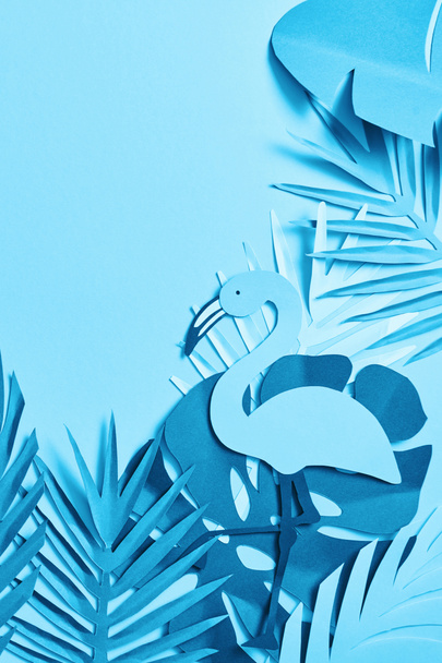 top view of blue minimalistic paper cut palm leaves and flamingo on blue background with copy space - Fotó, kép