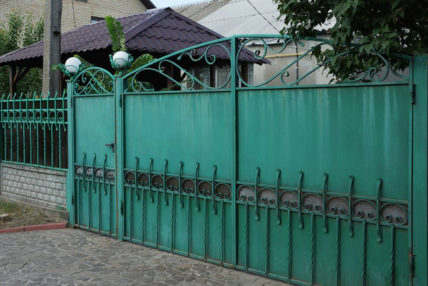 μακριά Πράσινη μεταλλική πύλη με σφυρήλατο μοτίβο στο δρόμο - Φωτογραφία, εικόνα