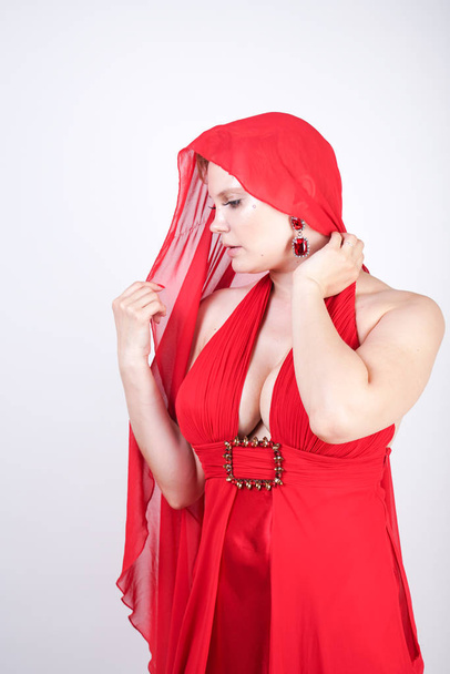 hot blonde caucasian woman wearing long red evening dress and posing on white studio background alone. fashionable adult girl with plus size body standing in stylish party clothes. - 写真・画像