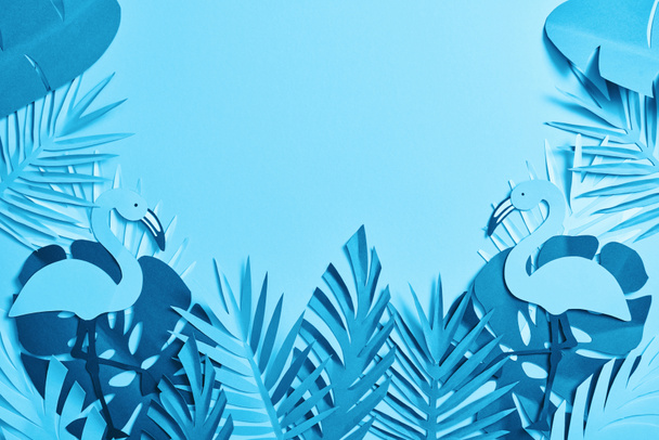 pohled na modrý exotický papír vyřezané palmové listy a plameňáky na modrém pozadí s prostorem pro kopírování - Fotografie, Obrázek