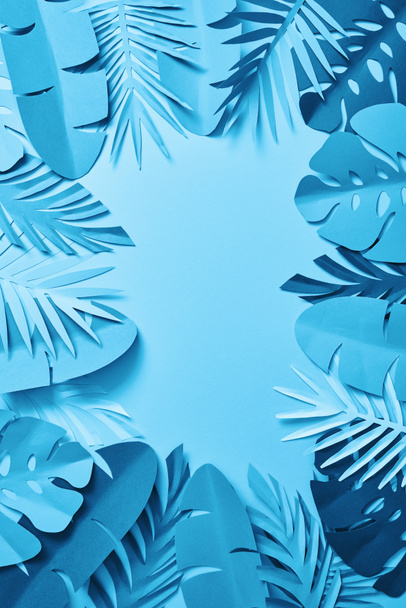 top view of blue exotic paper cut palm leaves on blue background with copy space - Foto, Imagem