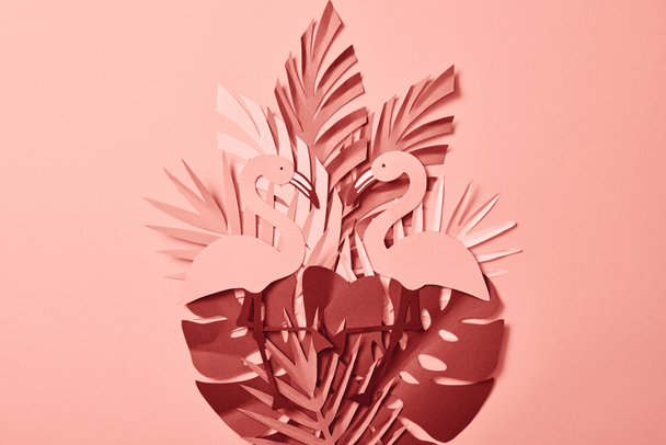 top view of pink exotic paper cut palm leaves and flamingos on pink background - Foto, afbeelding
