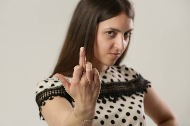 Mladá žena ukazující šroub, znamení prostředníčkem, rozzlobené gesto ženy, focení ve studiu - Fotografie, Obrázek