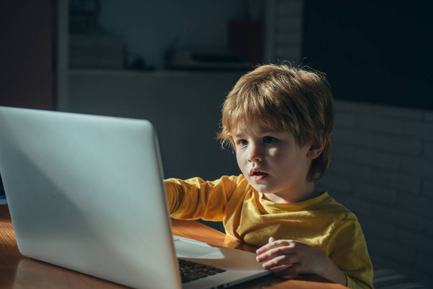 Cute schoolboy child playing and surfing online late at night. Child addicted to internet games and social media cant sleep looked on laptop. Digital technology in childhood and internet addiction. - Photo, Image