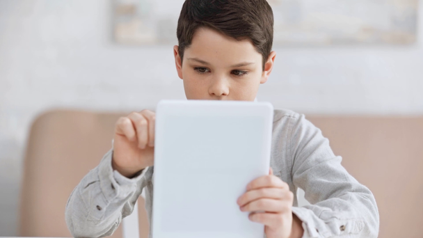 front view of pensive preteen boy using digital tablet and looking away - Footage, Video