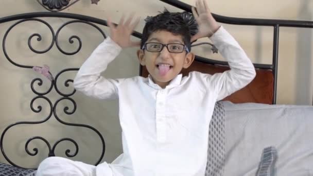Grappig spottende jongetje kind tong uit het maken van gezichten en hand gebaar dragen bril bril in woonkamer Vooraanzicht - Video