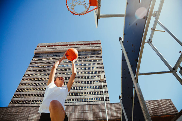 Girl playing basketball outdoors in the city - Fotó, kép