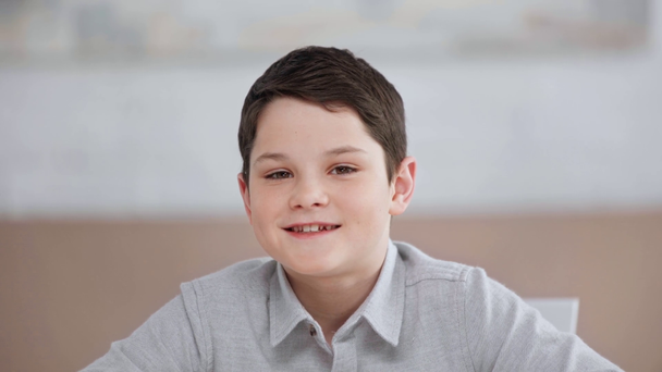 μπροστινή όψη του χαμογελαστή Προεφηβικό αγόρι αναβοσβήνει ενώ κοιτάζει την κάμερα - Πλάνα, βίντεο
