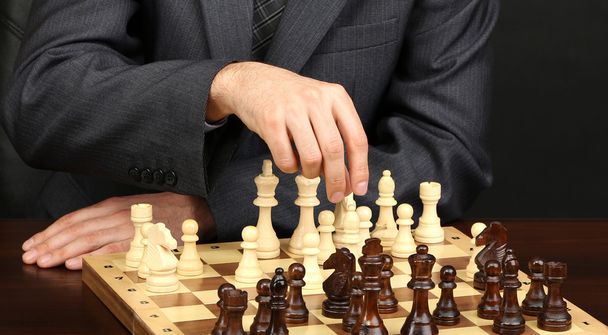 Young business man playing chess on black background - Zdjęcie, obraz