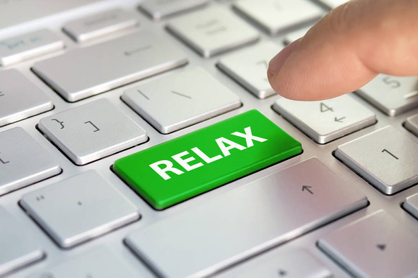Time to relax concept. word relax written on computer keyboard. Finger presses color button on the gray keyboard. Purchase buy tickets online. planning vacation online. Tourist agency. - Photo, Image