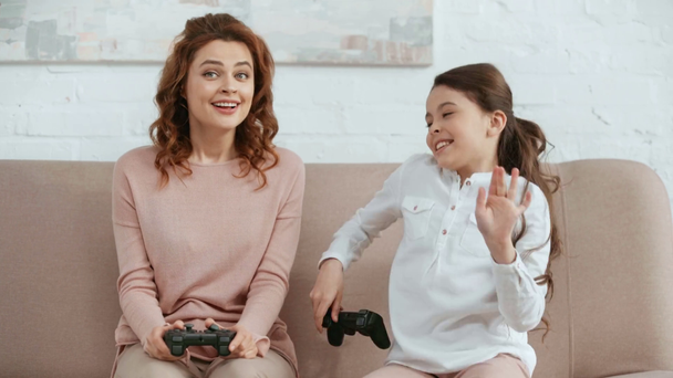 KYIV, UCRANIA - 15 DE ABRIL DE 2019: un niño emocionado jugando un videojuego con su madre, disfrutando de la victoria y sonriendo mientras su madre acaricia su cabeza
 - Metraje, vídeo