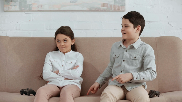 Kijów, Ukraina-15 kwietnia 2019: dwa podekscytowany dzieci trzymający joystick i gry wideo, siedząc na kanapie w salonie - Materiał filmowy, wideo