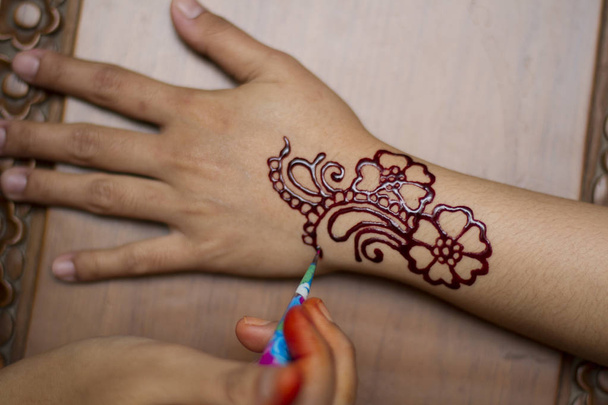 Master toepassing henna op vrouwelijke hand - Foto, afbeelding