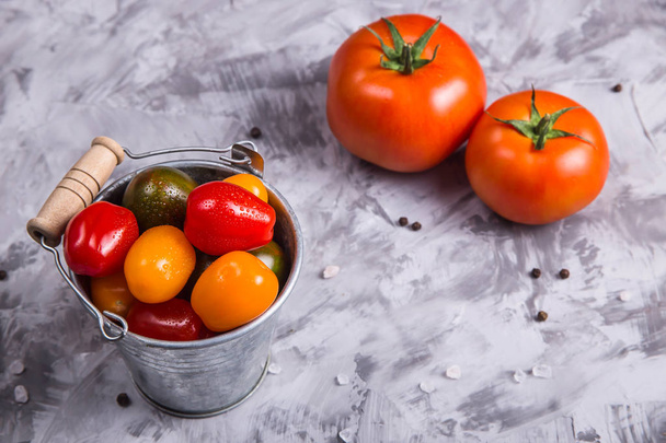 Rijpe tomaten voor het koken van groente schaal op een grijze achtergrond - Foto, afbeelding