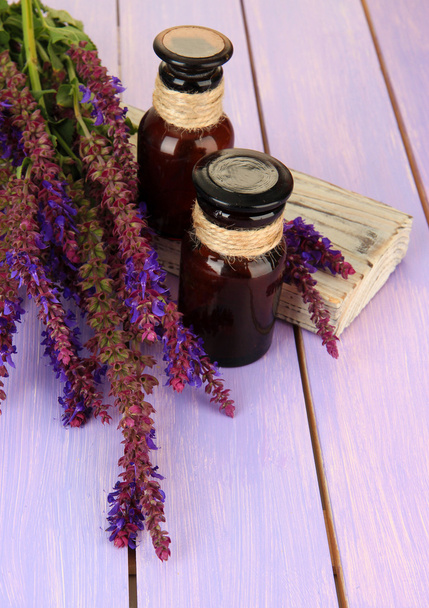 Botellas de medicina y flores de salvia sobre fondo de madera púrpura
 - Foto, imagen