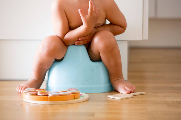 Little toddler boy, sitting on potty, playing with wooden toy - 写真・画像
