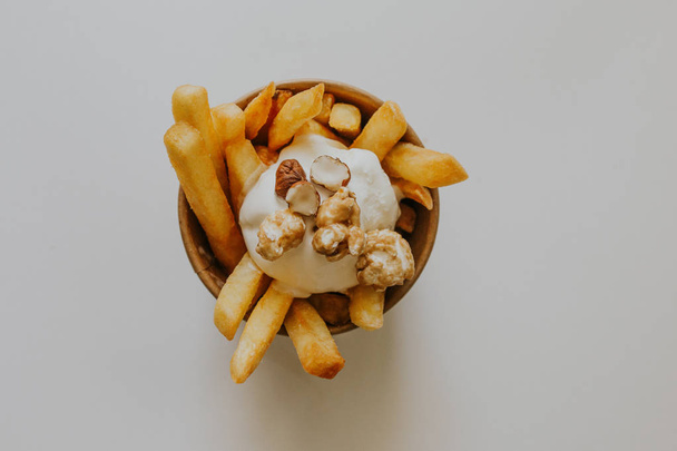 top view of tasty french fries with creamy sauce and nuts on grey - Zdjęcie, obraz