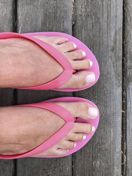 pés de uma mulher usando chinelos rosa
 - Foto, Imagem
