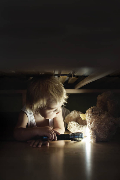 Little child, hiding under the bed, hugging teddy bear and holdi - Φωτογραφία, εικόνα