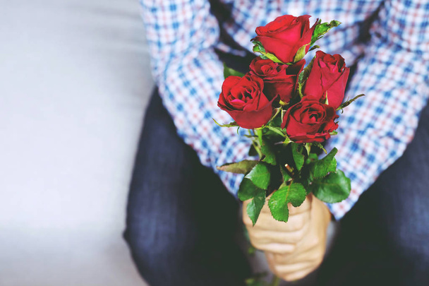 Przystojny mężczyzna Plaid shirt rękę trzymając się bukiet pięknych z czerwonym kwiat róży. Walentynki koncepcji. miękka ostrość. - Zdjęcie, obraz