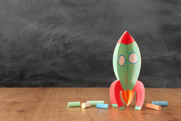 education and back to school concept. cardboard rocket and chalks in front of classroom blackboard - Foto, Bild