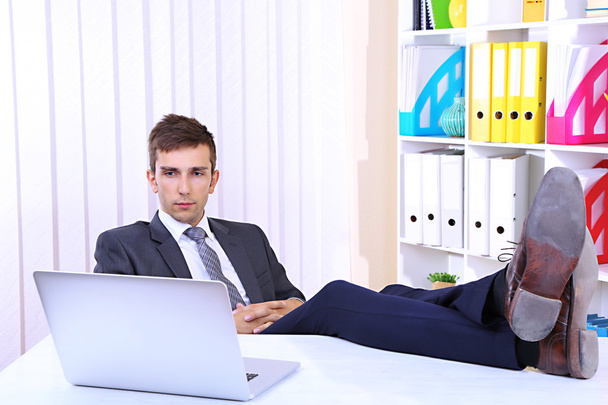 Empresario descansando en su oficina con sus zapatos en la mesa
 - Foto, Imagen