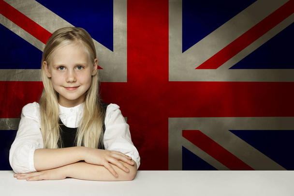 Joyeux enfant étudiant assis en classe sur le fond du drapeau britannique. Apprendre la langue anglaise concept
 - Photo, image