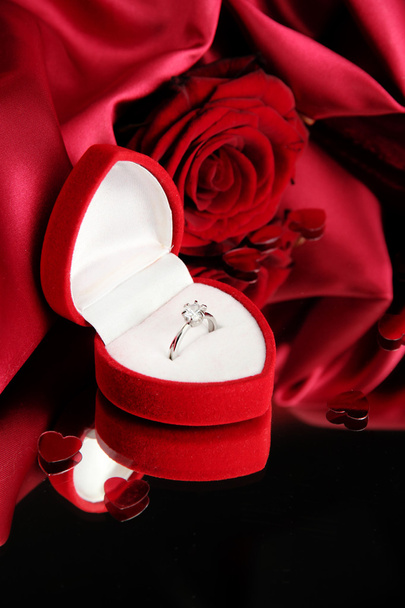 Beautiful box with wedding ring and rose on red silk background - Фото, изображение